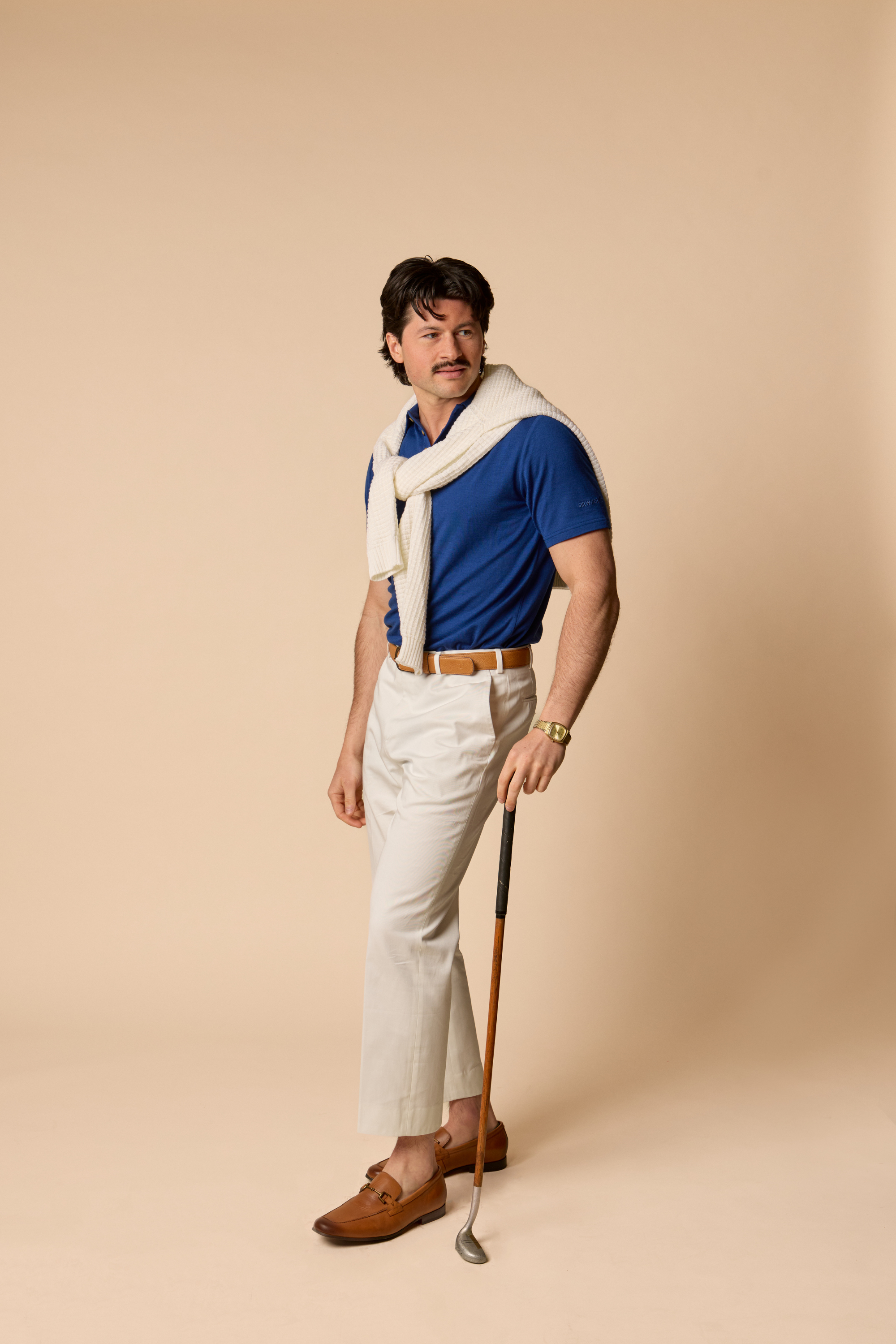 Sir W. Merino George polo in navy blue, front view, modeled by man standing with golf club