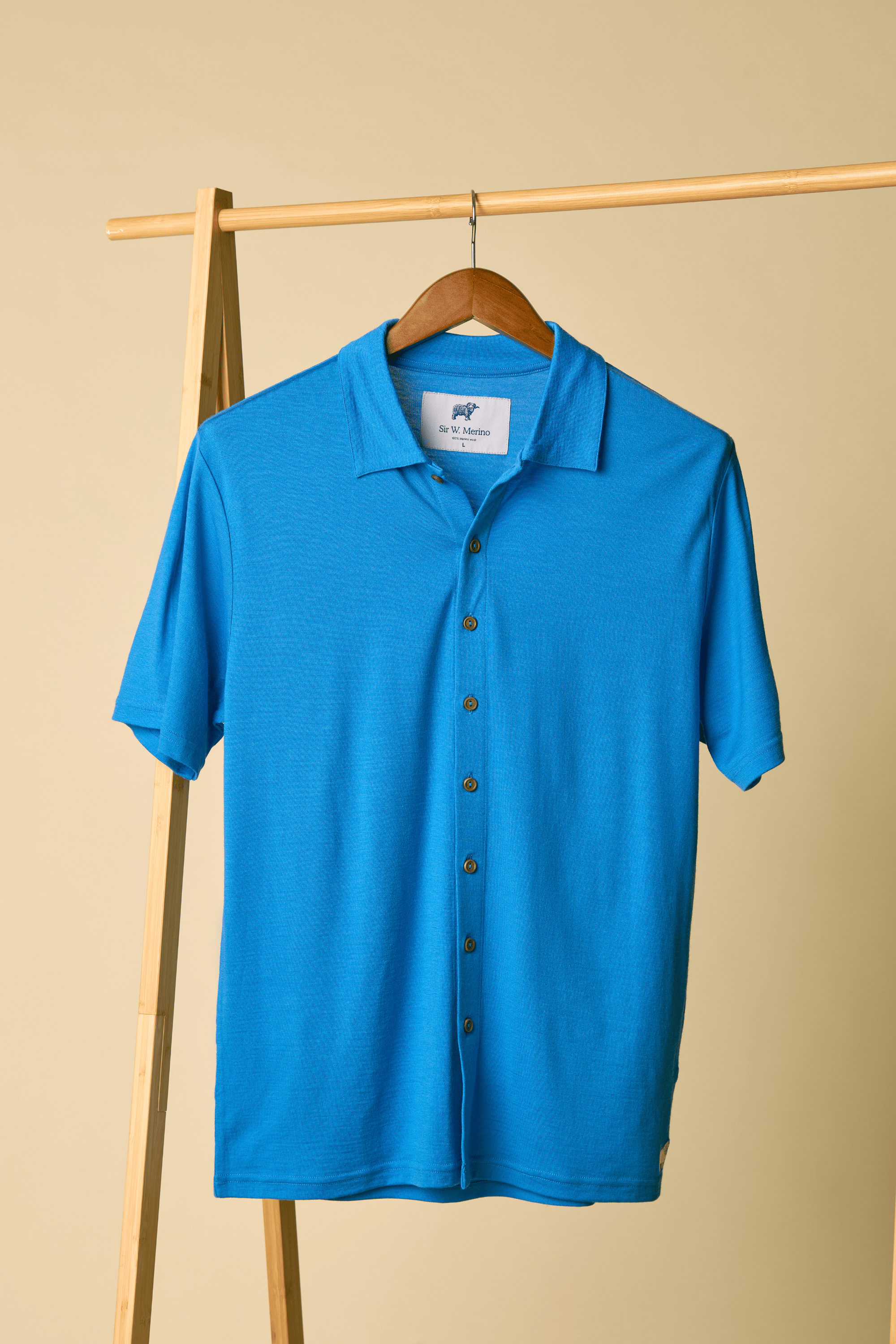 Sir W. Merino Bruce French Blue shirt on a hanger against a beige background