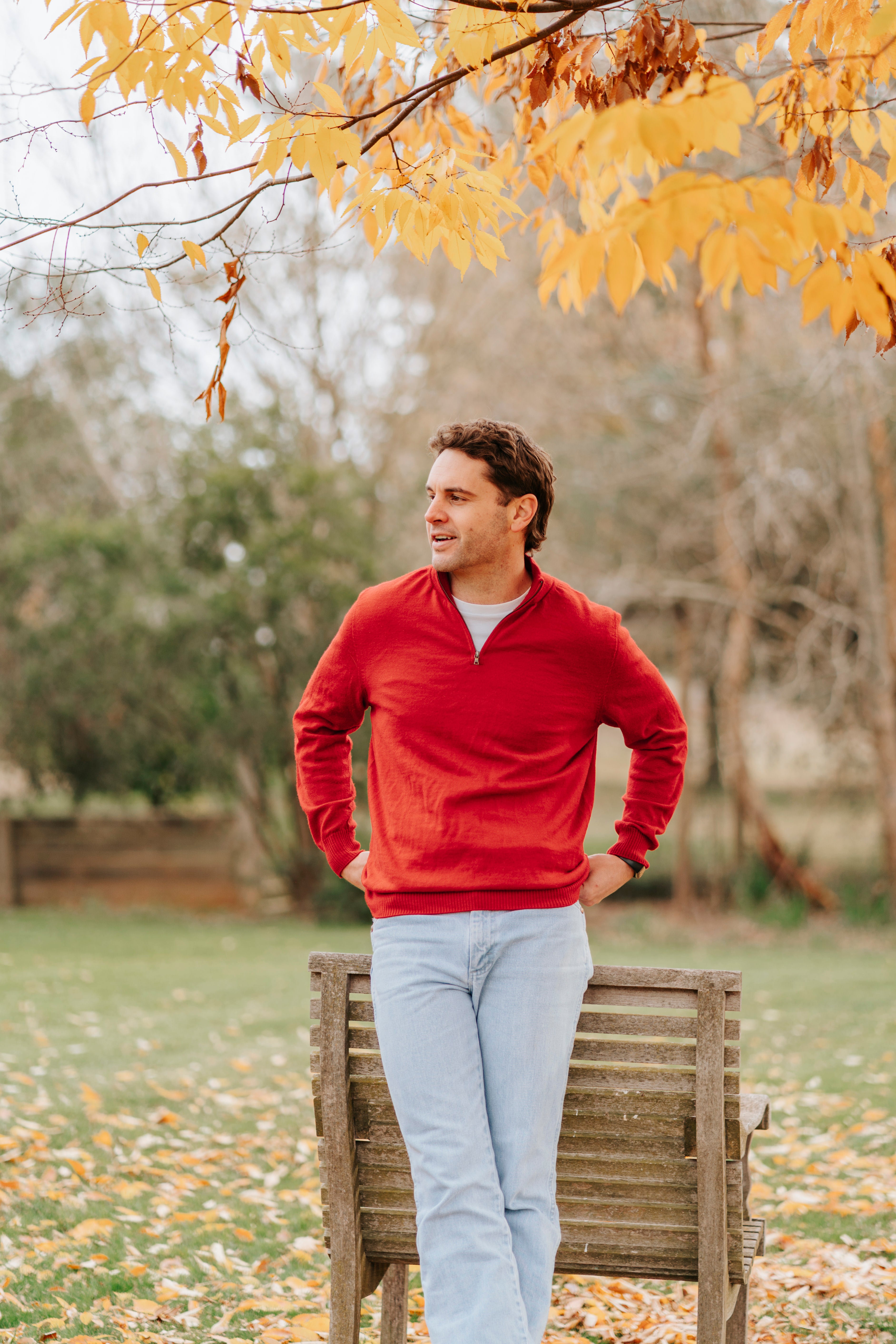 Man wearing a red Merino wool sweater and light blue jeans