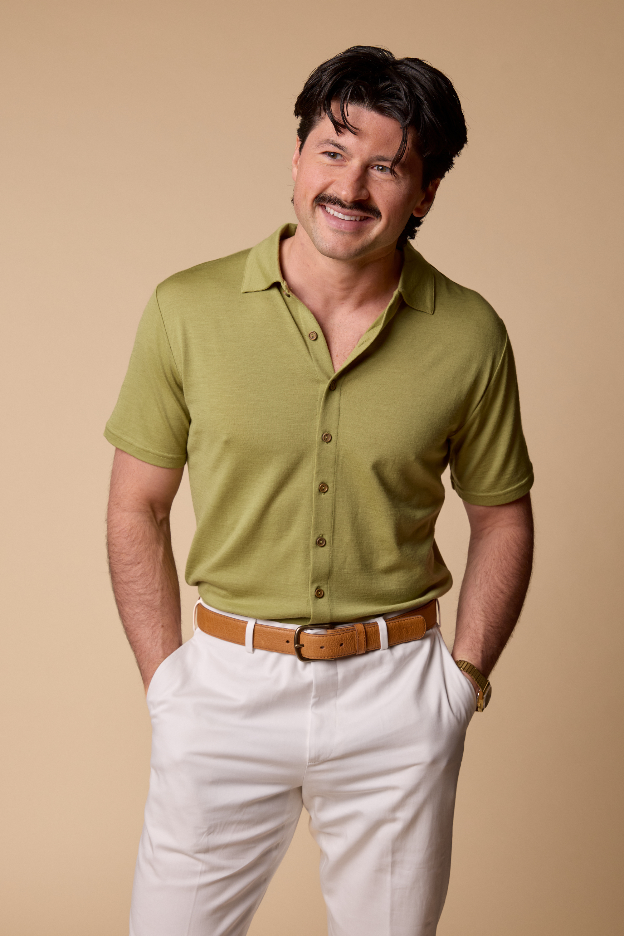 Man wearing a Sir W. Merino Bruce Olive Green shirt and white pants with a brown belt