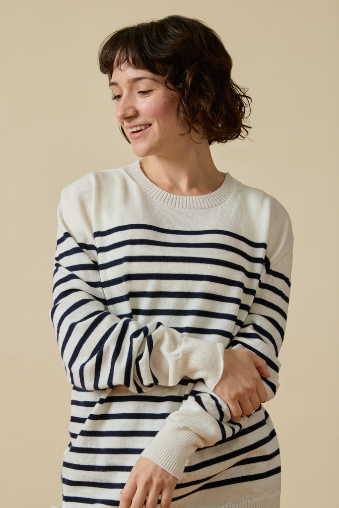 Woman wearing a black and white striped Sir W. Merino sweater against a beige background