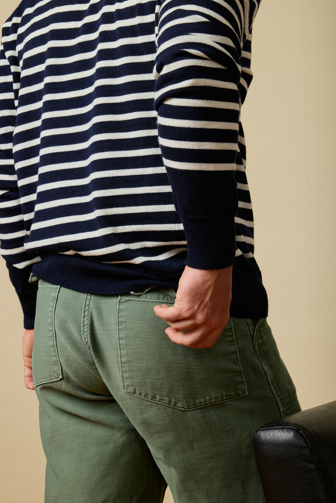 Person wearing a striped Sir W. Merino sweater and green pants against a beige background