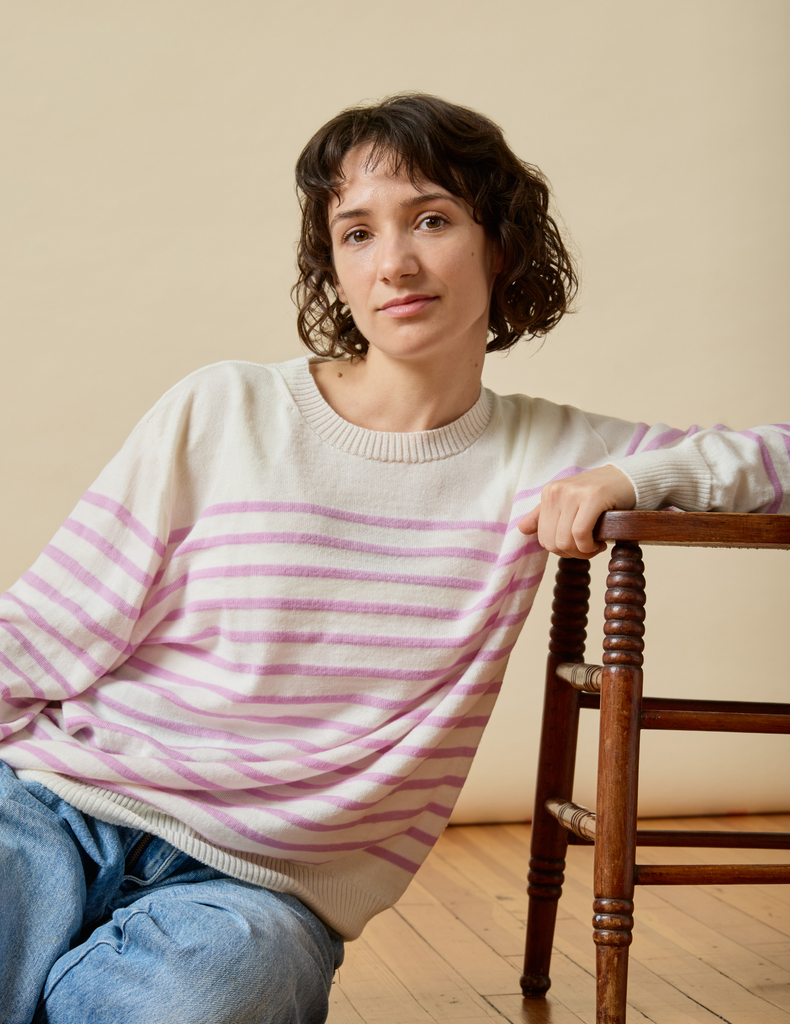 Woman wearing a striped Merino wool sweater sitting on a wooden floor.