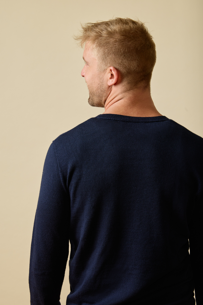 Man wearing a navy Merino wool long-sleeve shirt against a beige background
