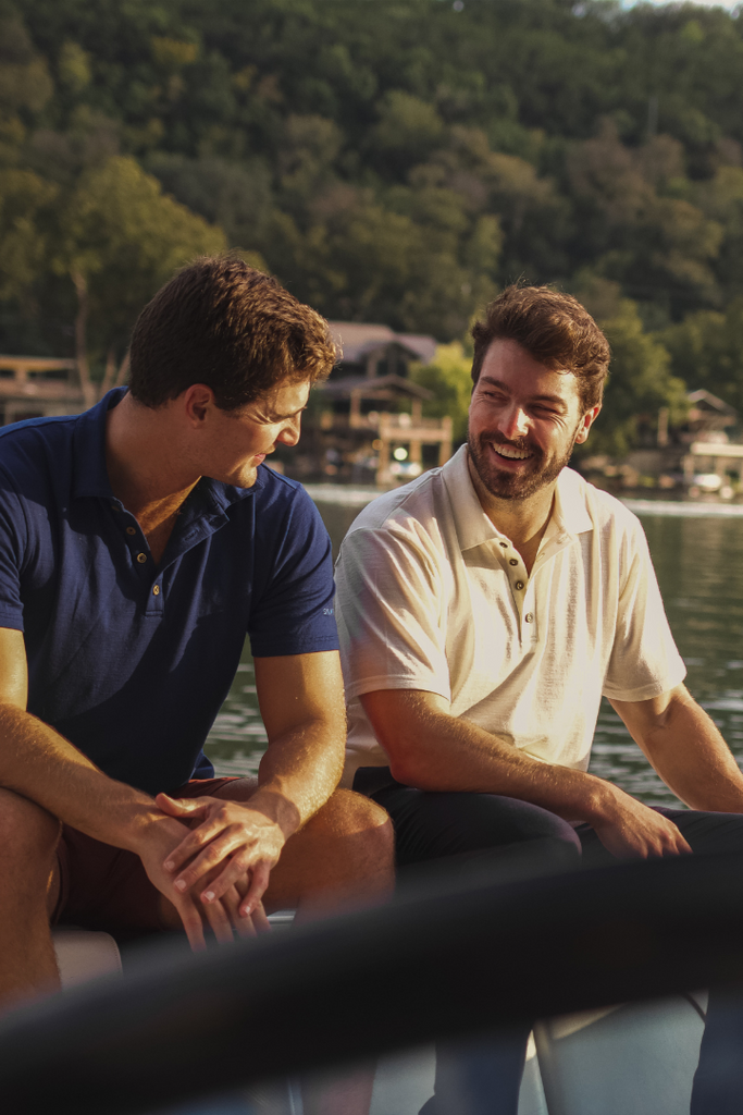 Man wearing a merino polo laughing on a boat
