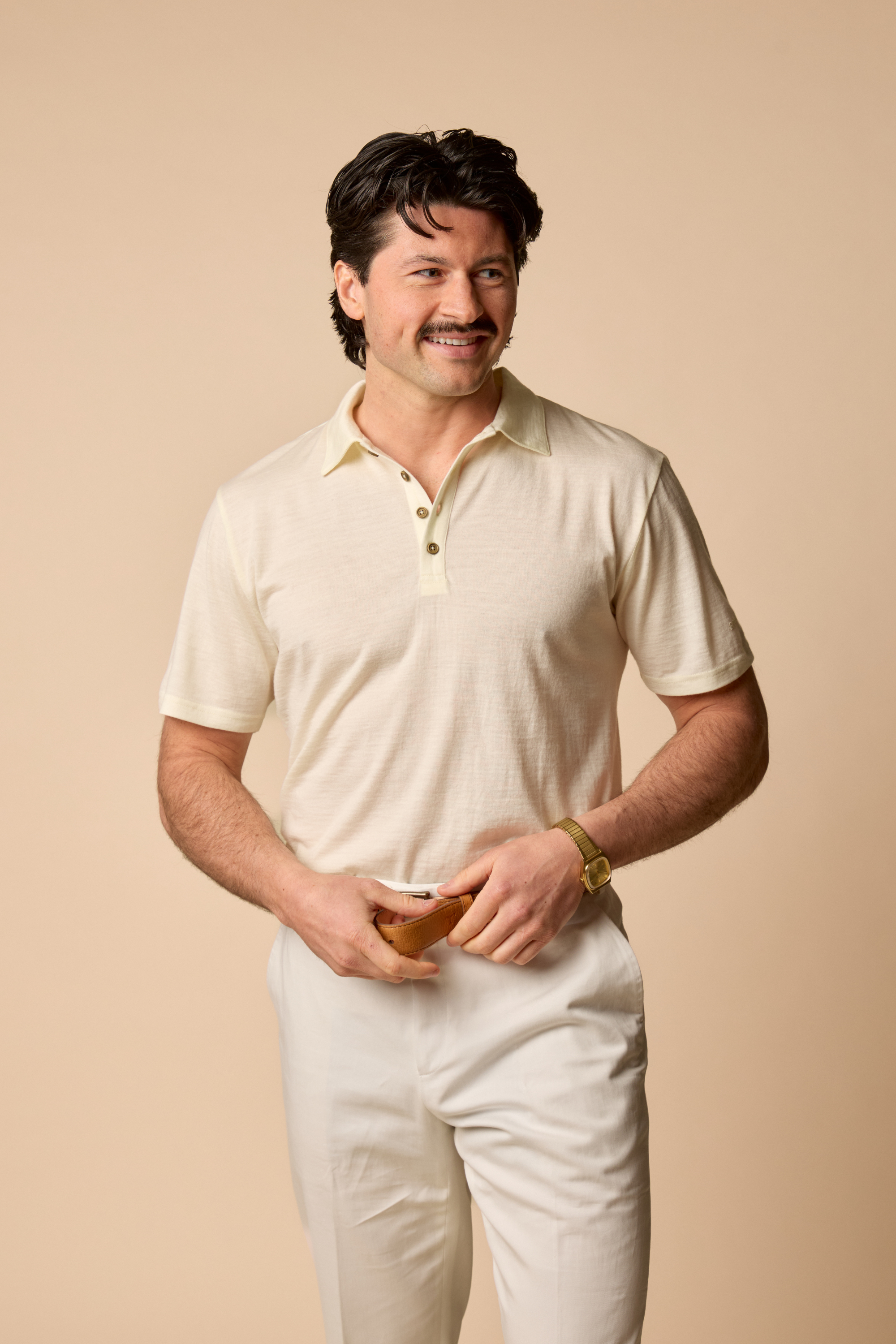 Man wearing a Sir W George polo shirt and pants against a beige background