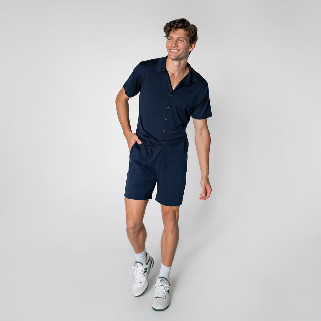 A person wearing navy blue merino wool lounge shorts with a matching Merino wool shirt