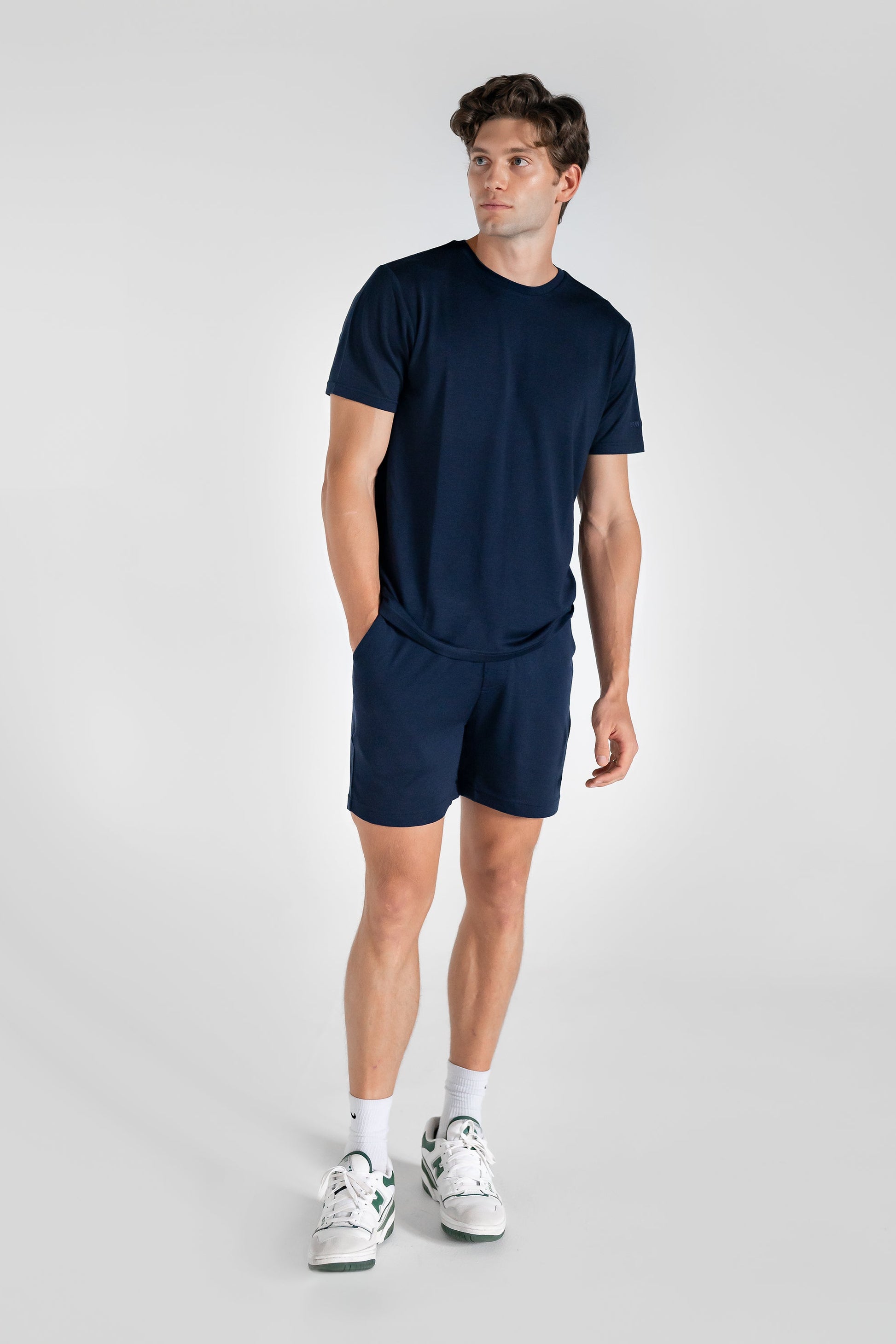 A person wearing navy blue merino wool lounge shorts with matching navy merino tee