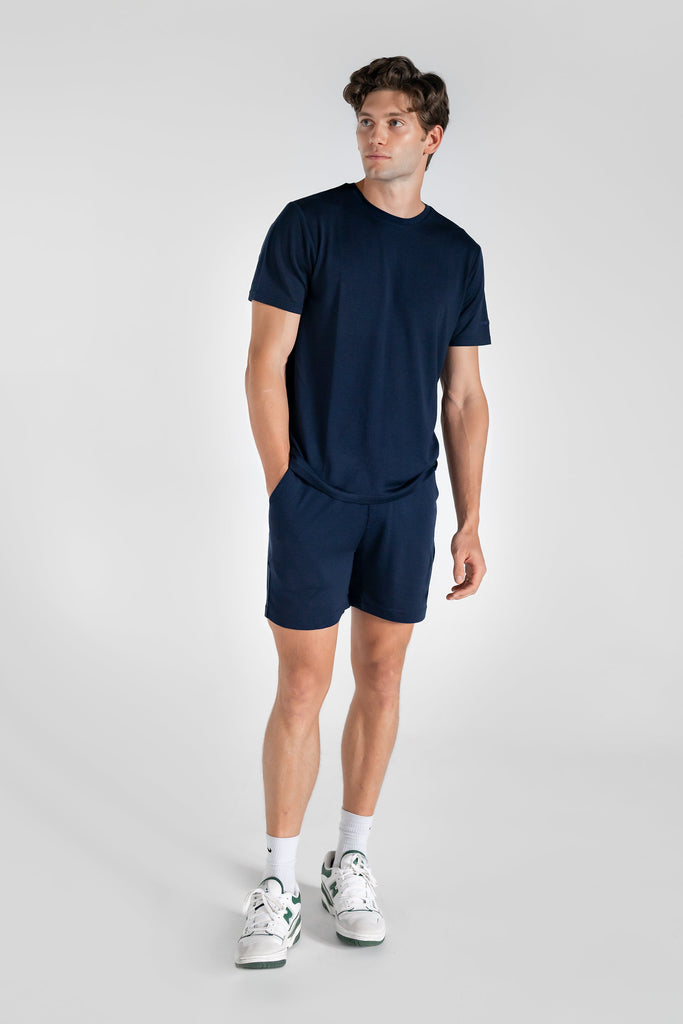 A person wearing navy blue merino wool lounge shorts with matching navy merino tee