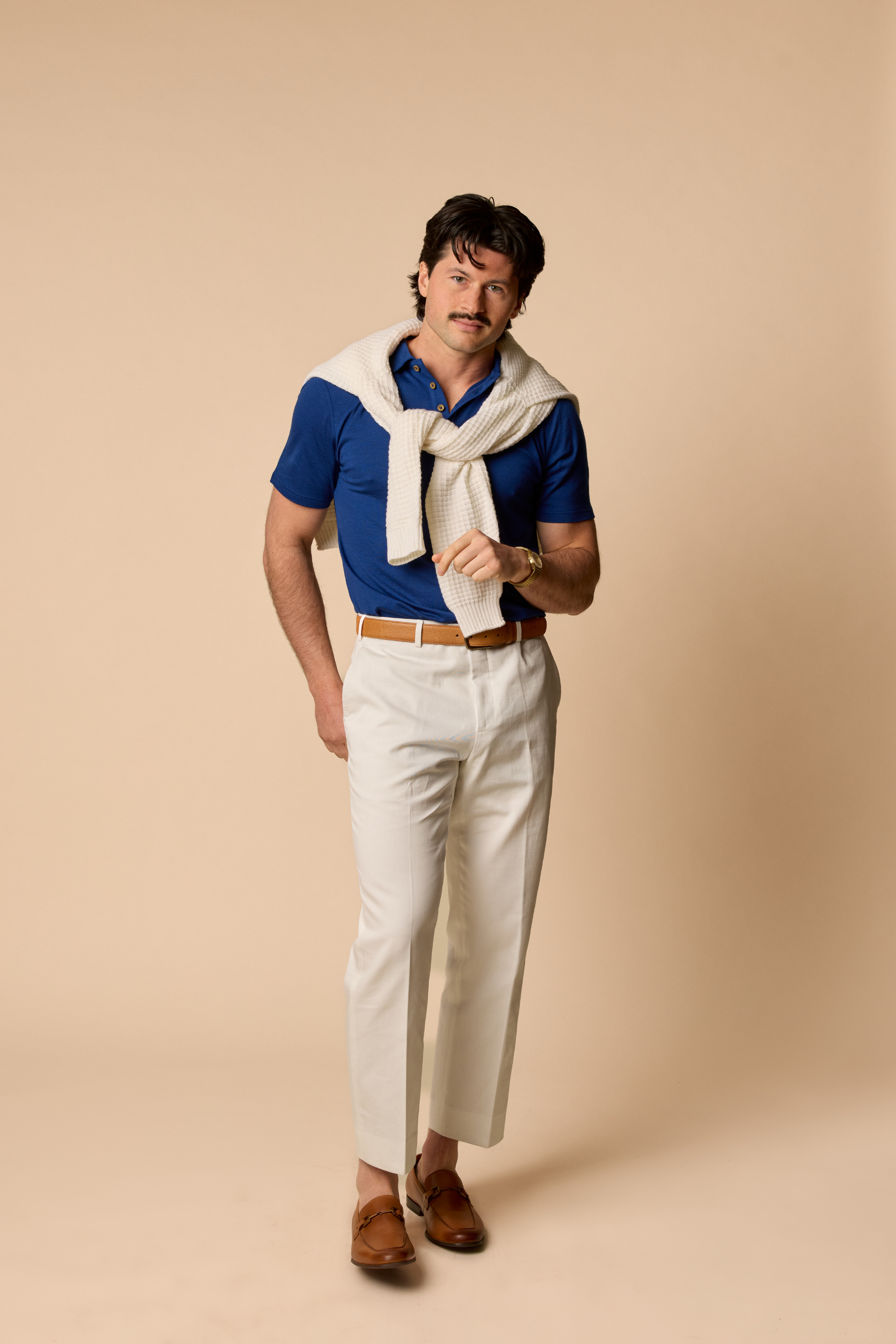 Sir W. Merino George polo in navy blue, front view, modeled by man standing with white sweater accessory