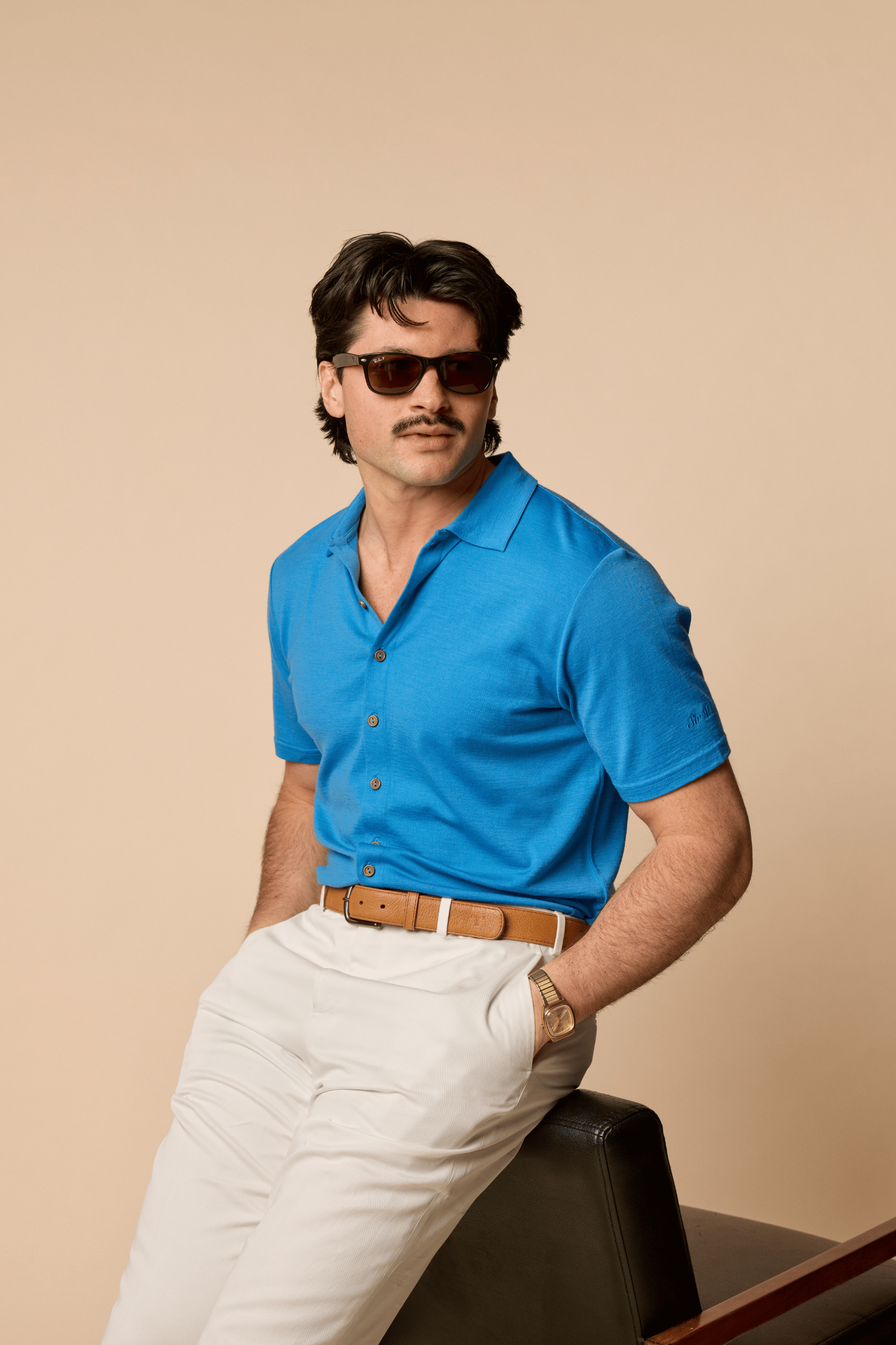 Man wearing Sir W. Merino Bruce French Blue shirt and sunglasses against a beige background
