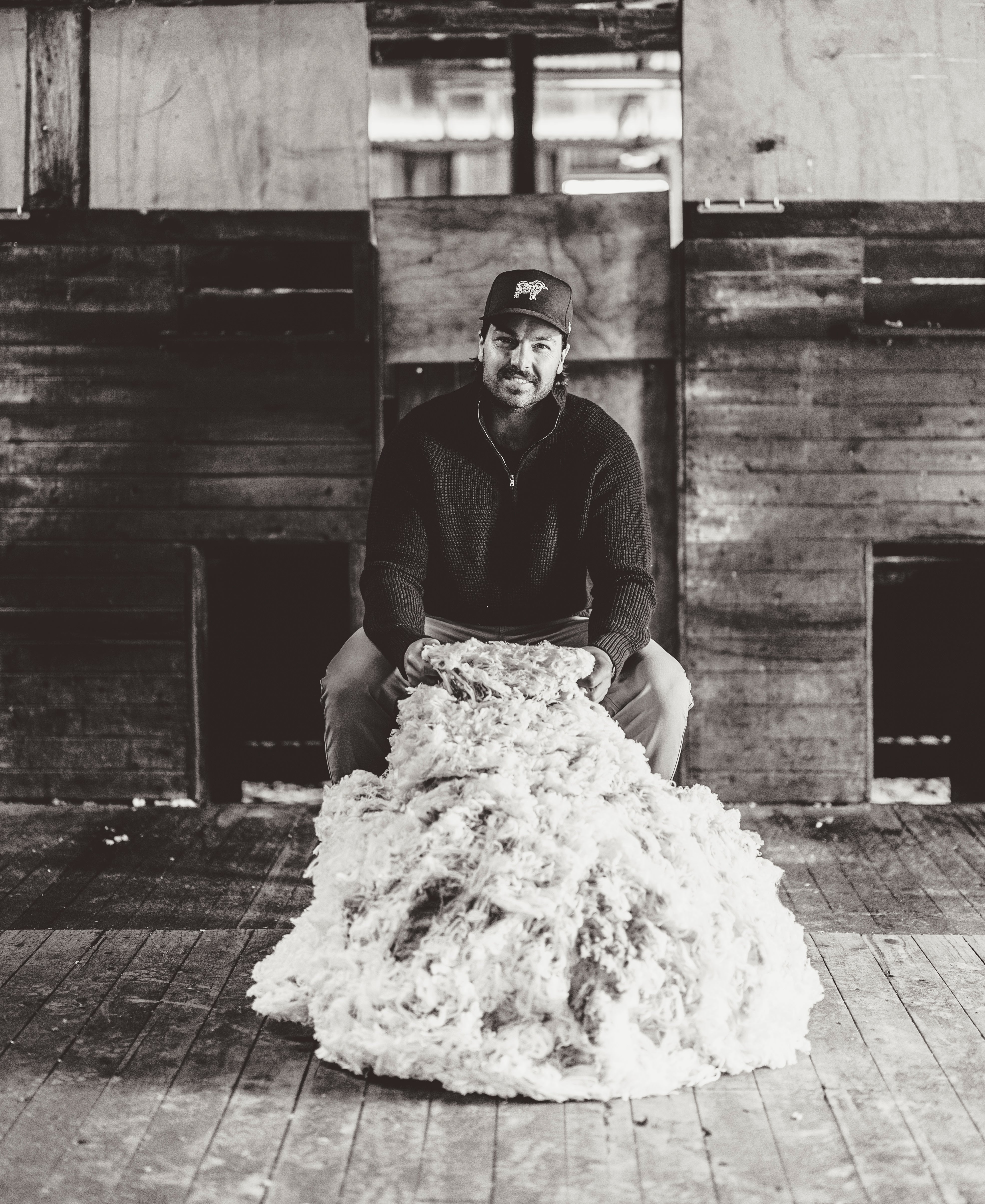 Founder of Sir W. Merino, Jock Merriman sits in a shearing shed with a Merino wool fleece.