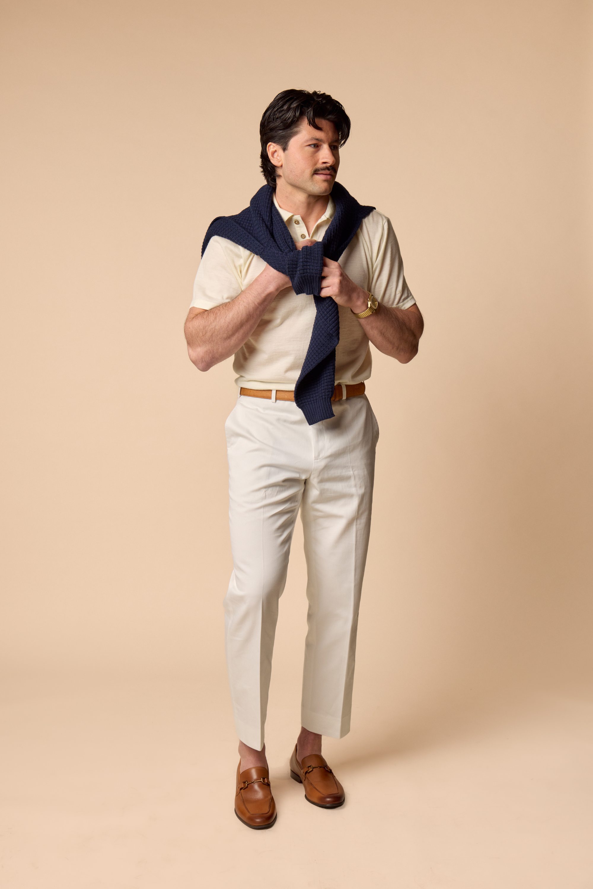 Man wearing natural Sir W Merino polo adjusting a navy sweater 
