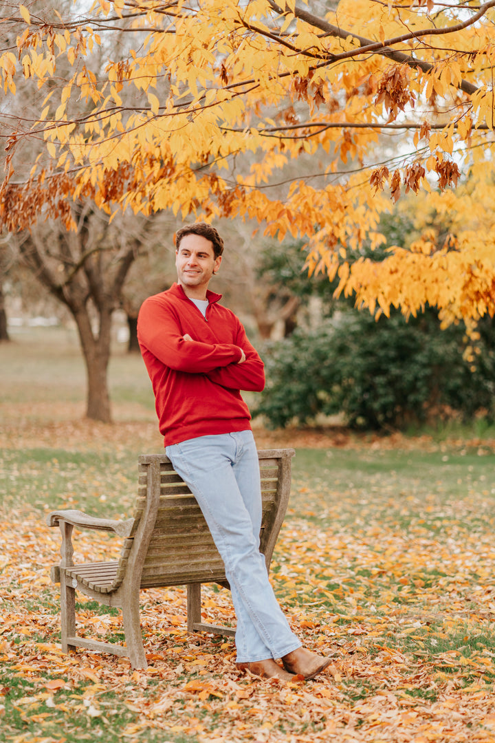 Man wearing a red Merino wool sweater and light blue jeans 