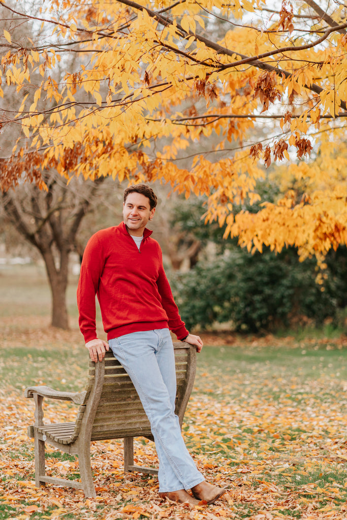 Man wearing a red Merino wool sweater and light blue jeans 