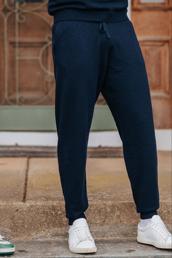 Two men standing on steps in front of a house, wearing matching tracksuits.