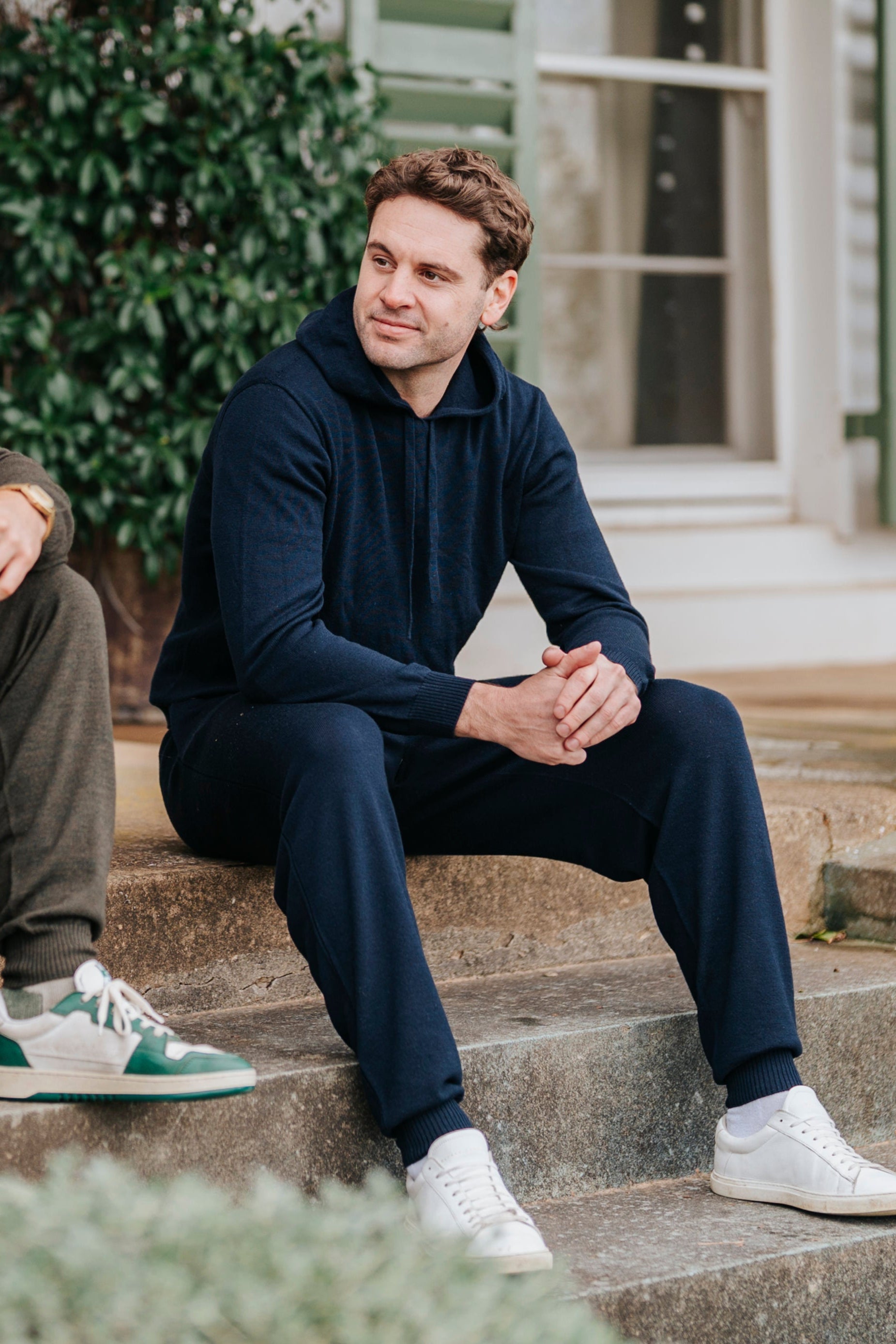 Two men sitting on a porch steps in front of a house.