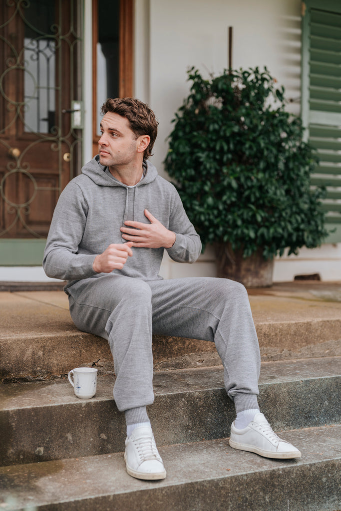 Man wearing Grey Merino wool Sweatpants sitting on steps with a cup, outdoor setting