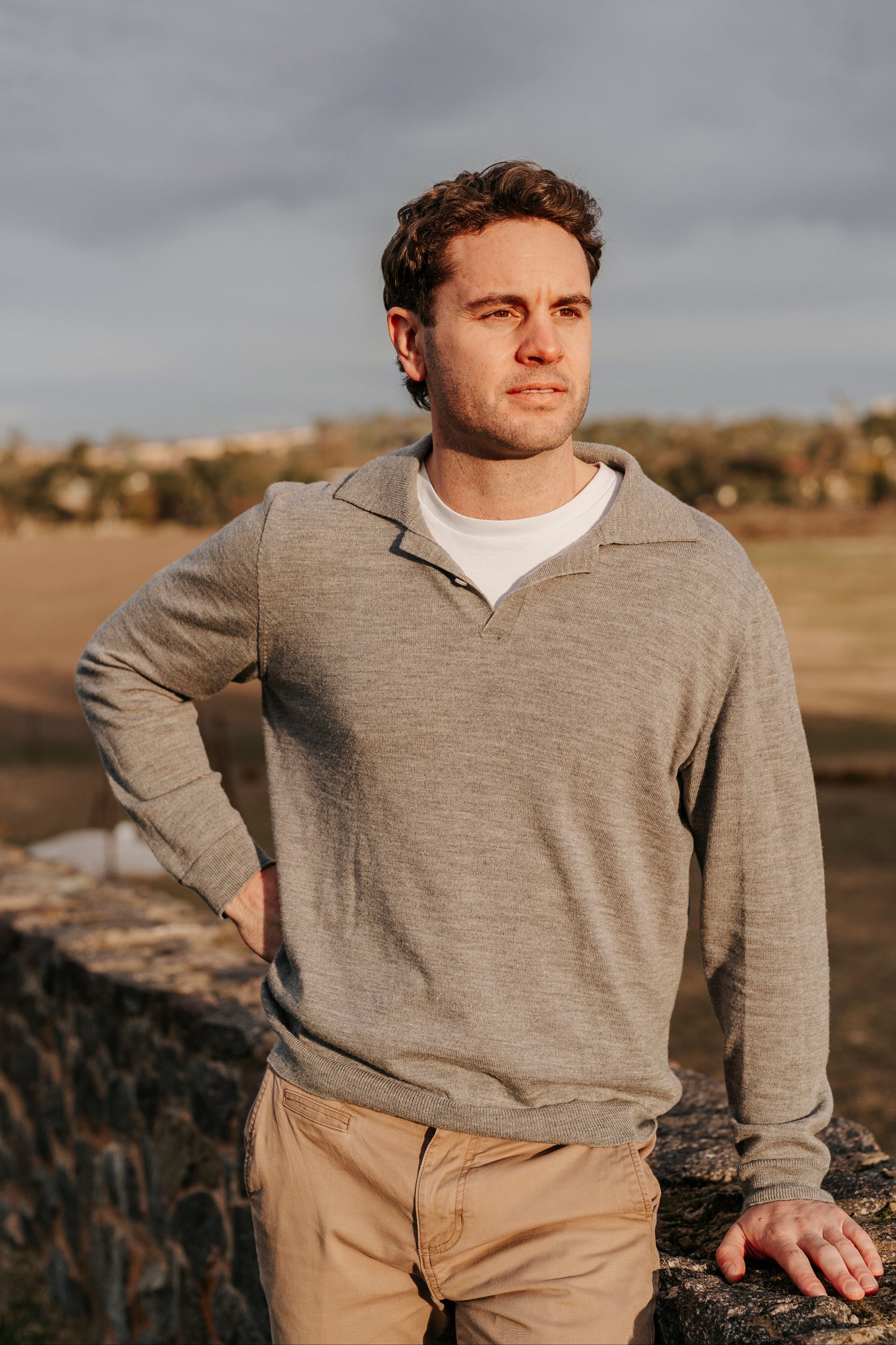 Man standing outdoors with a cloudy sky in the background