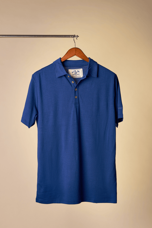 Sir W. Merino Royal Blue polo shirt on a wooden hanger against a beige background