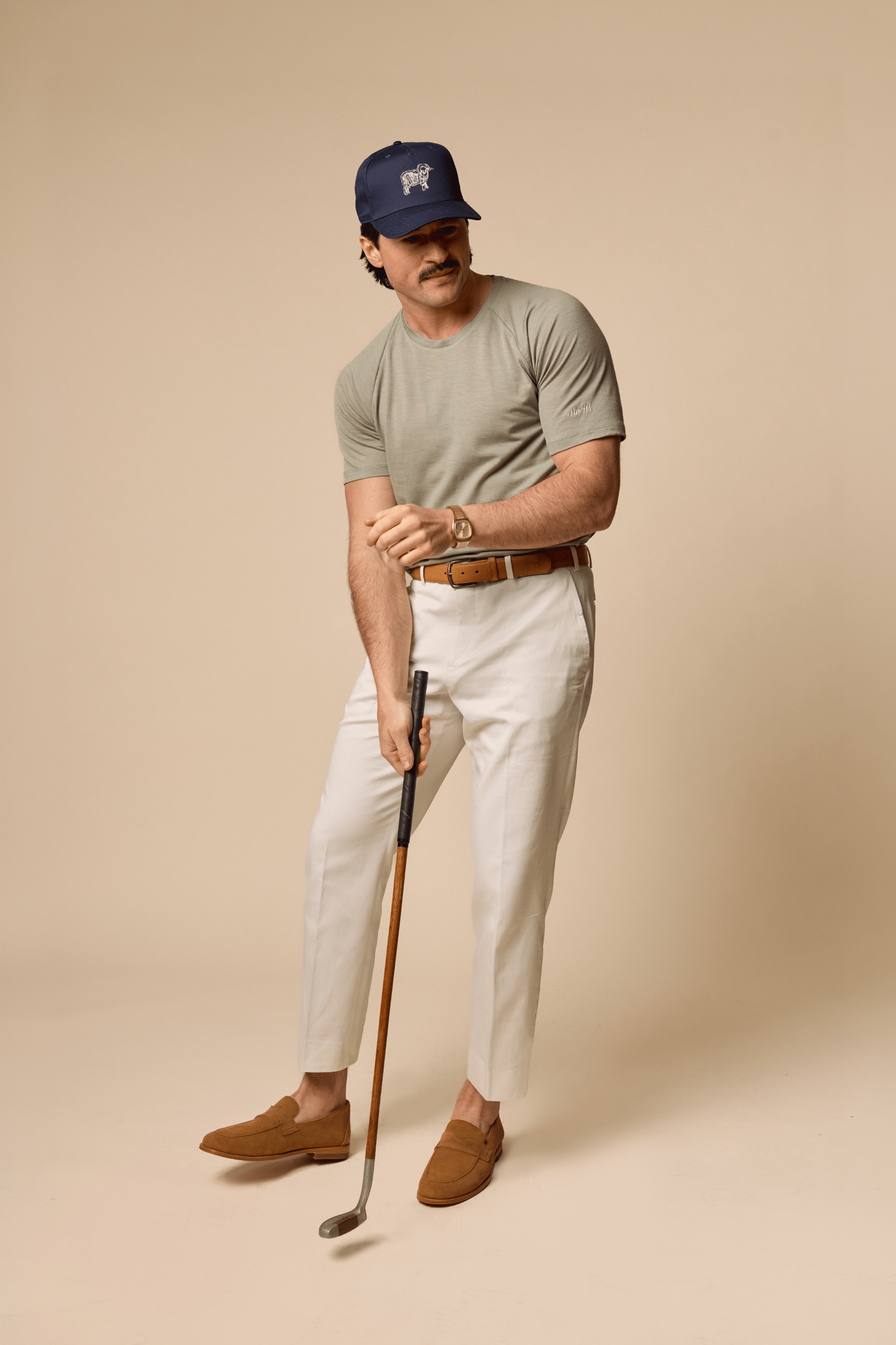 Man wearing Sir W. Merino cassius shadow grey tee and white pants with navy Sir W. cap.
